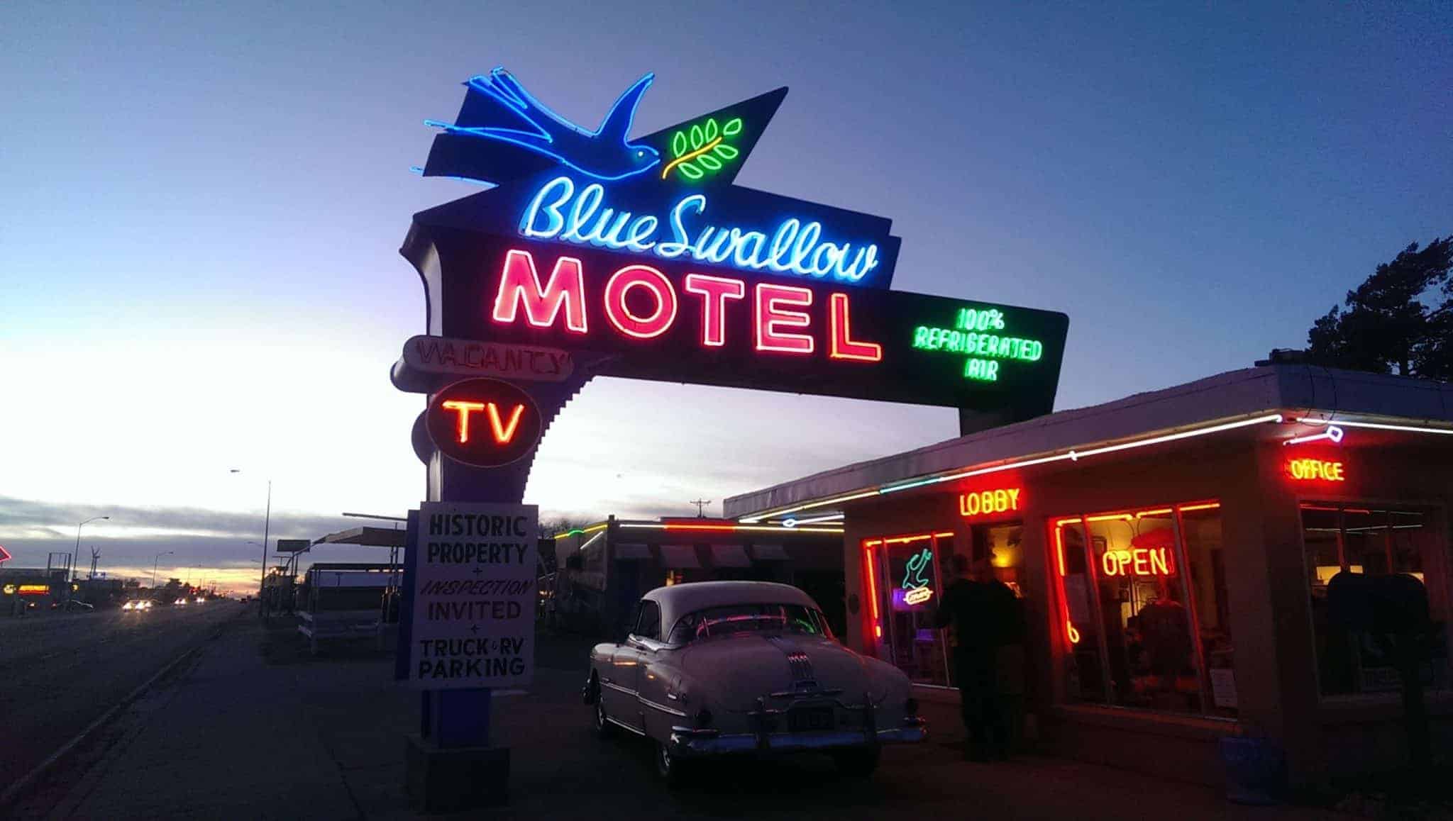 neon Blue Swallow Motel sign lit in twilight